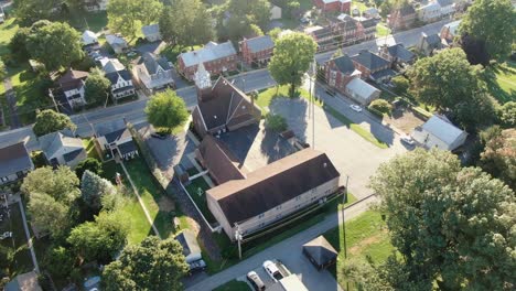 aerial orbit of church building with steeple, new and old sections, along small town road in pennsylvania