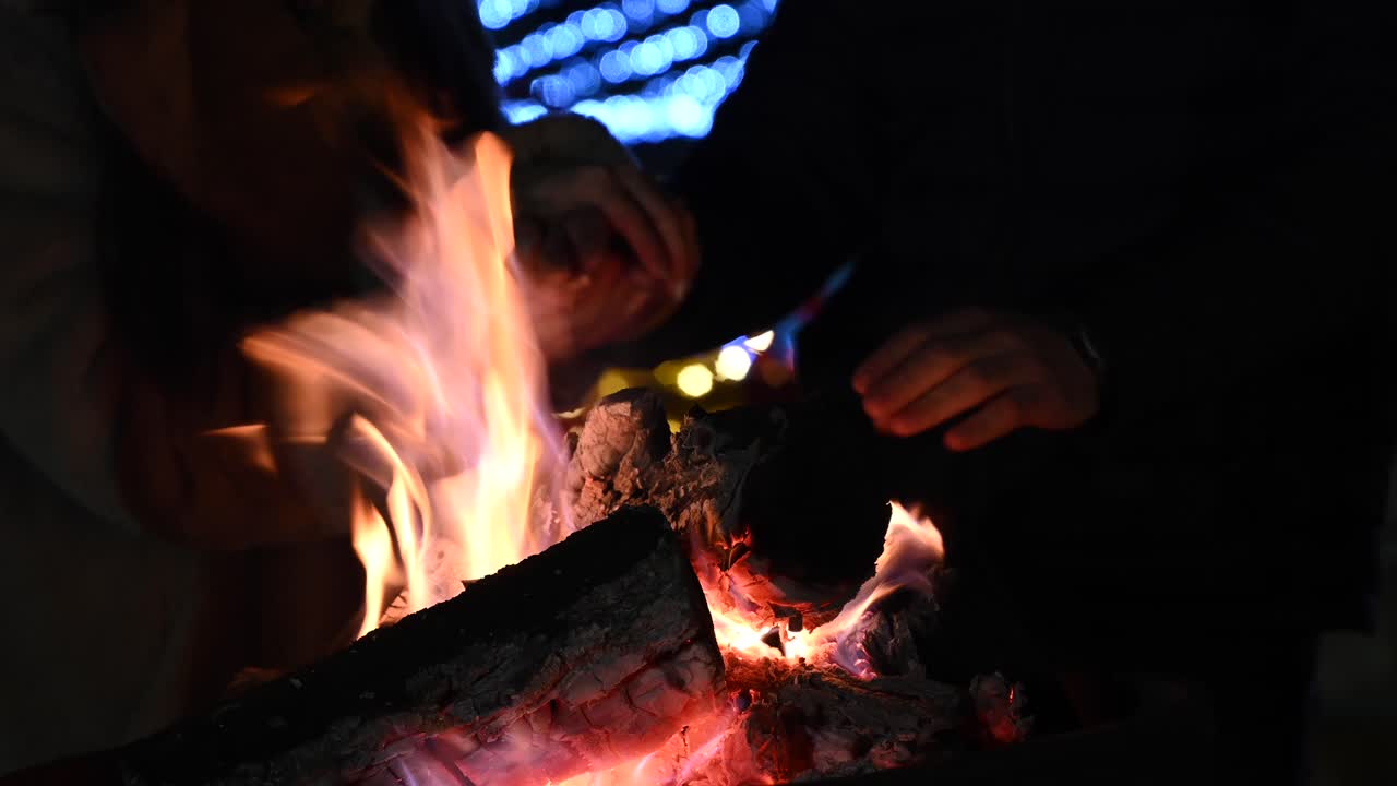 Close up of people warming their hands on a fire burning outside
