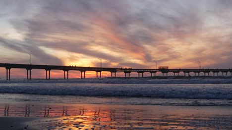 pier in sea water on beach. ocean waves, sky at sunset. california coast vibes.