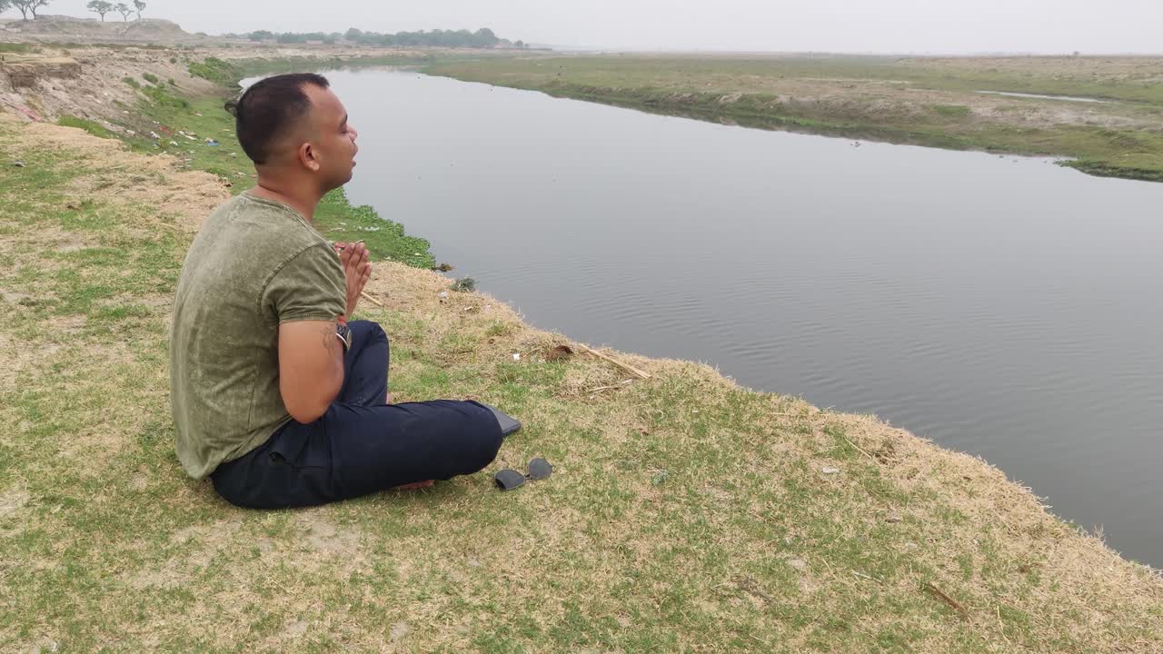 여름 아침 바다 앞에서 연꽃 자세로 앉아 요가를 연습하고 열린 들판에서 기도하는 소년의 뒷모습