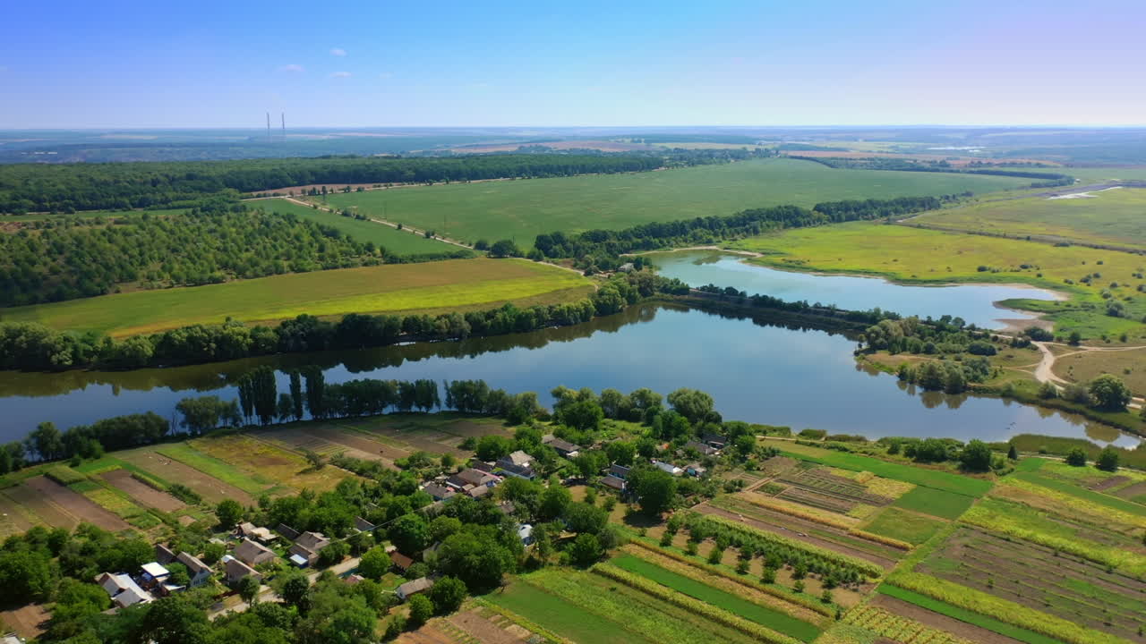 Little river floating in the green fields. Beautiful small village locating on the picturesque river bank. Top view.