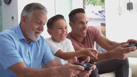 Männliche-Hispanische-Familie-Mit-Mehreren-Generationen,-Die-Zu-Hause-Videospiele-Spielt-Und-Zusammen-Auf-Dem-Sofa-Sitzt