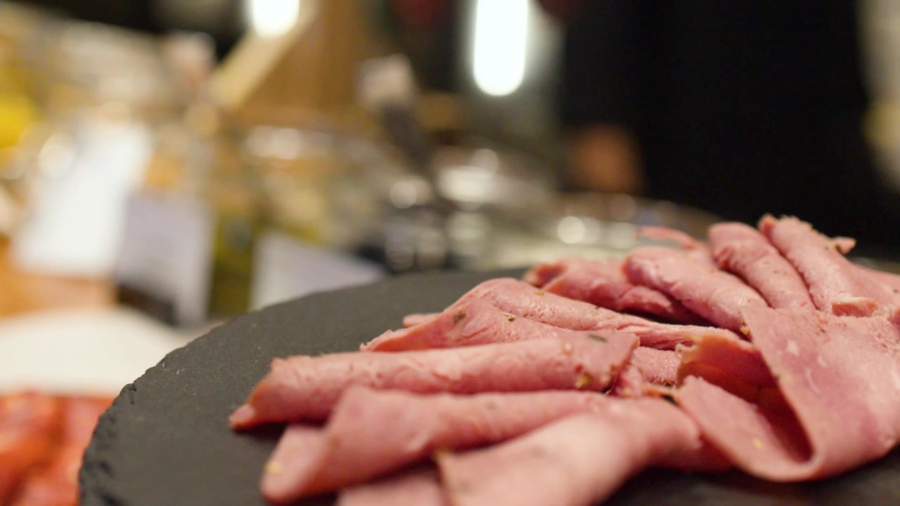 Un primo piano di roast beef tagliato finemente disposto su un piatto di pietra nera