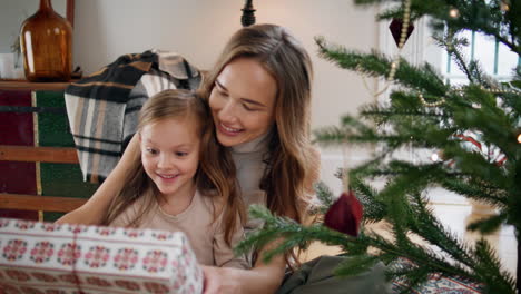 Fürsorgliche-Mutter-überreicht-Ihrer-Kleinen-Tochter-Ein-Geschenk,-Gemütlicher-Ort.-Mädchen-Sucht-Geschenk