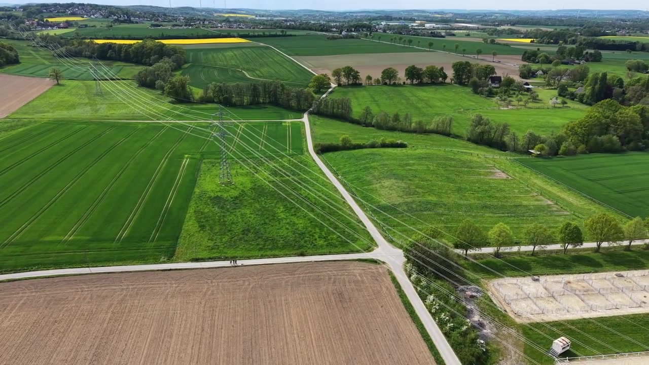 Vast green and brown agricultural fields stretching across a rural landscape under a partly cloudy sky