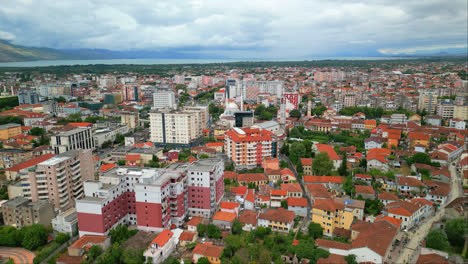 Aerial-drone-shot-flying-over-the-city-buildings-in-Shkodra,-also-known-as-Shkoder-or-Scutari-in-northwestern-Albania-on-a-cloudy-day