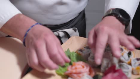a roaming shot follows from a sushi chef’s face to him placing sushi rolls onto a decorative board, showcasing the precision and artistry of sushi presentation. ideal for culinary and sushi content.