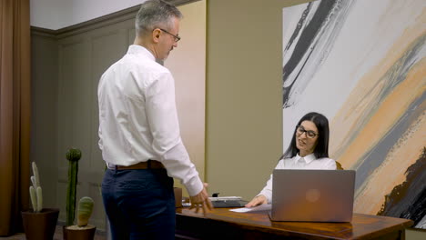 male employee giving document to his boss, shaking hands with her and then leaving