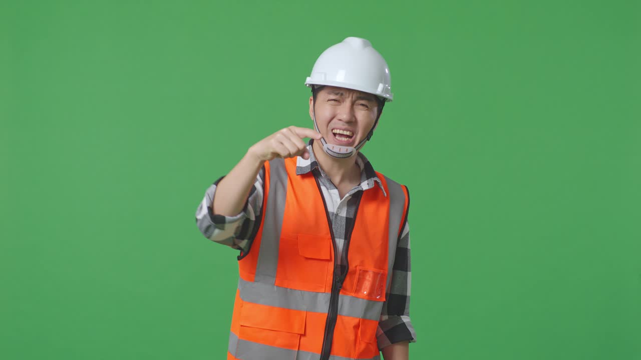 Angry Asian Male Engineer With Safety Helmet Shouting At Someone While Standing In The Green Screen Background Studio