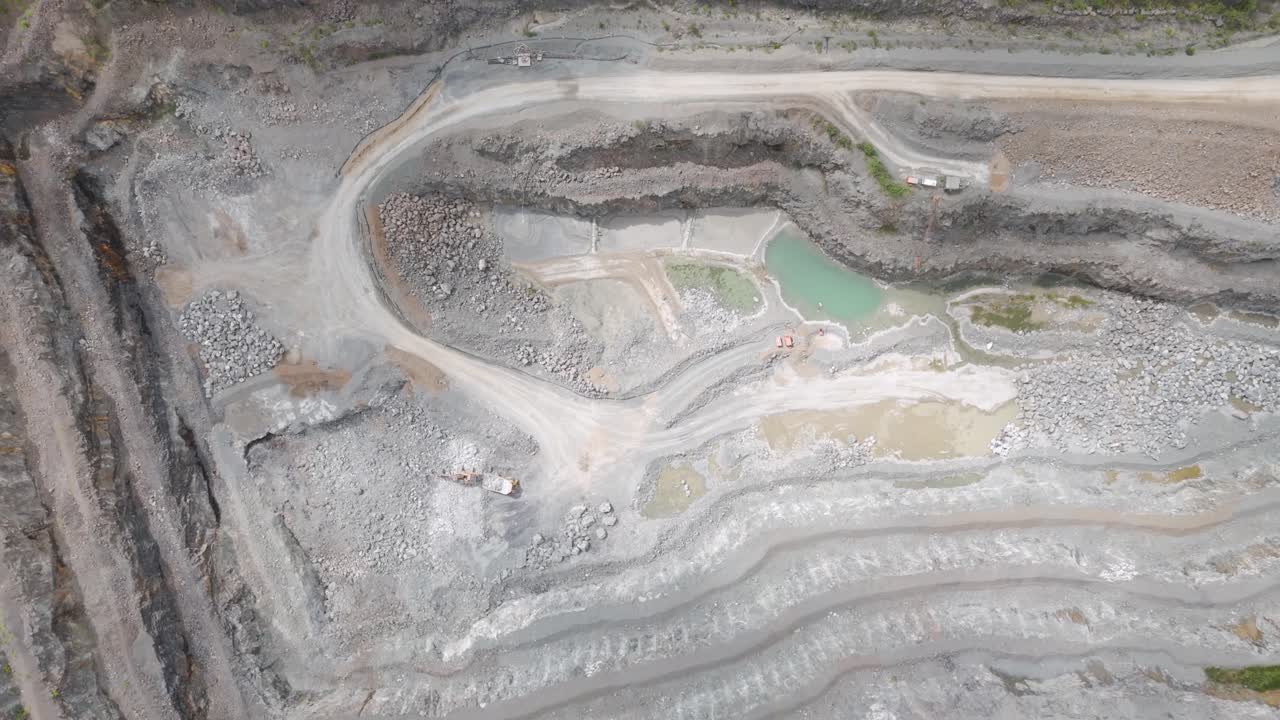Aerial view of a large open-pit quarry with terraced levels and industrial equipment