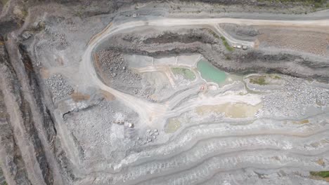 aerial view of a large open-pit quarry with terraced levels and industrial equipment