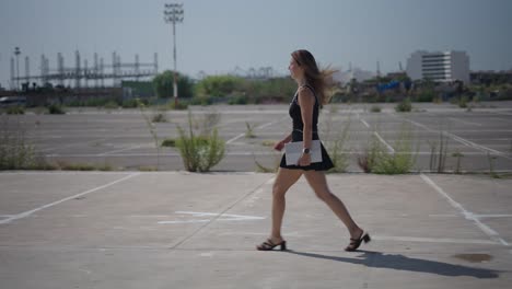 woman walking with laptop in urban parking lot