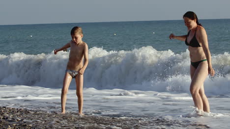 mother and son playing in the ocean waves