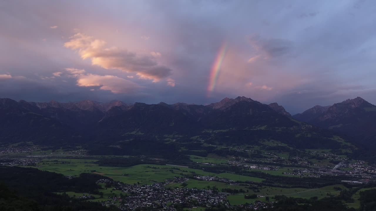 Drone fly in Austrian Mountains during Sunrise with Rainbow in the Background