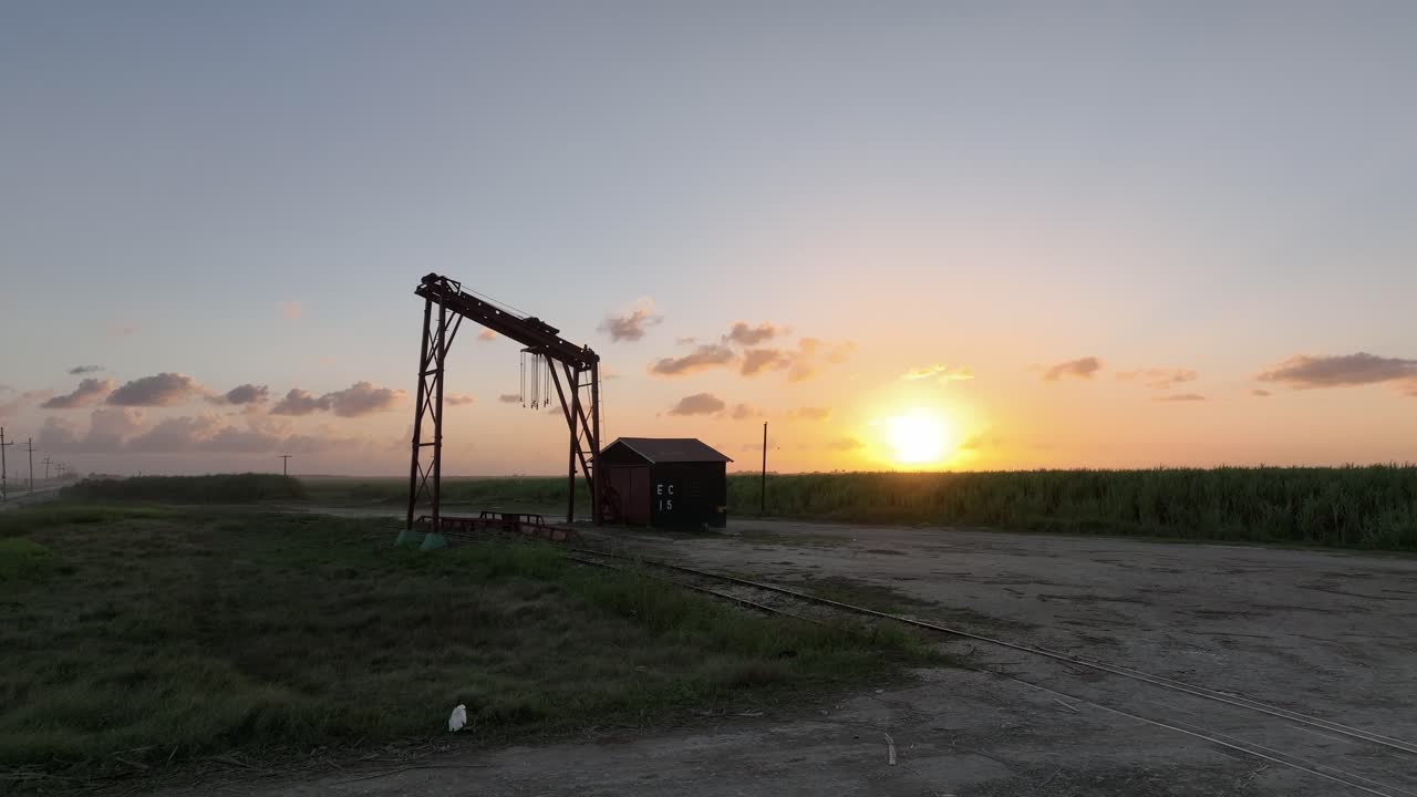 vista aérea de una grúa en una vía de tren para cargar productos agrícolas, puesta de sol en higueral, en la república dominicana