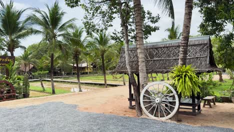 a serene view of a rustic farm museum with lush greenery and traditional structures under bright daylight in phuket
