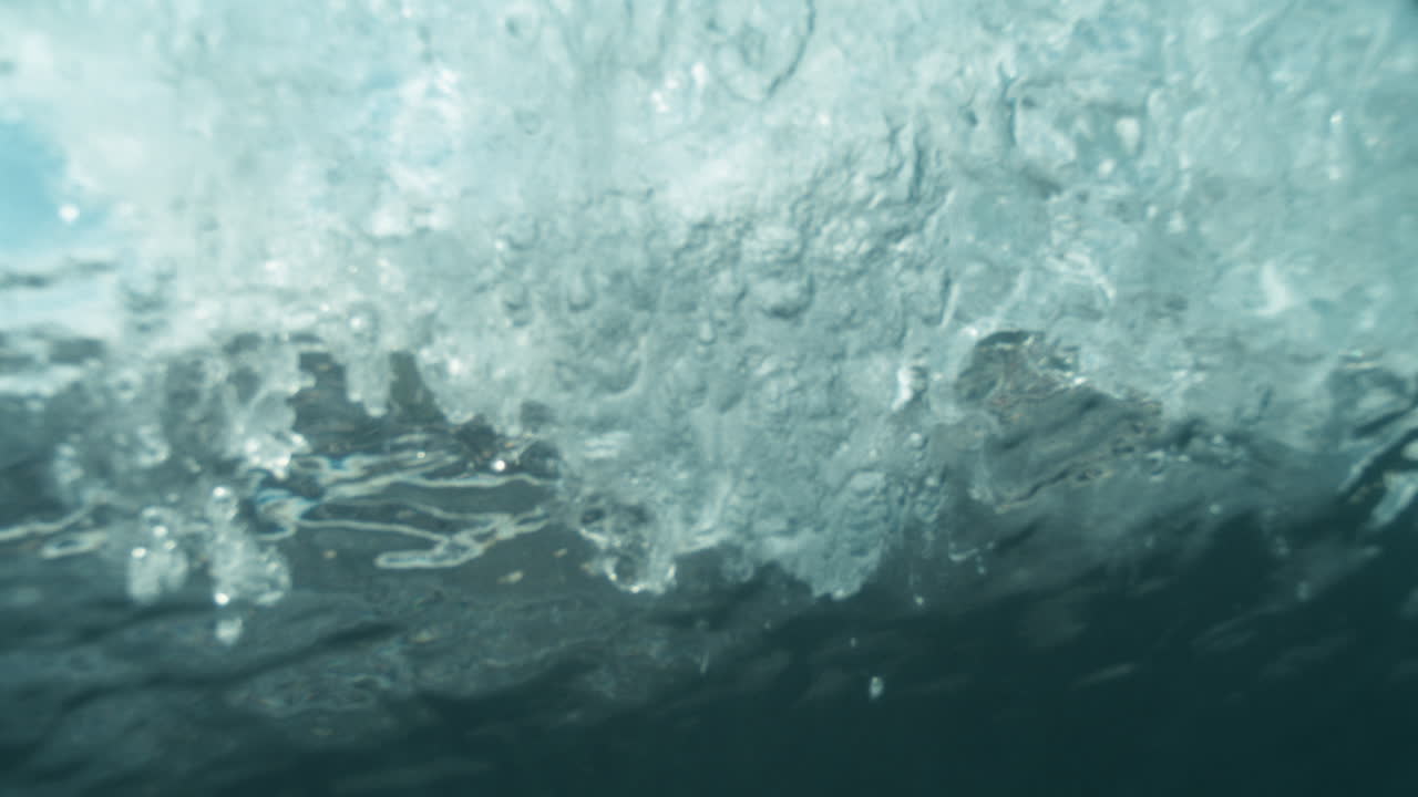 Super slow motion of underwater wave textures, light glistens through surface above