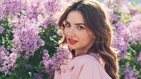 woman in a pink jacket surrounded by lilacs