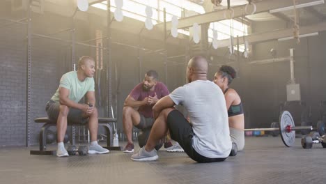 grupo feliz diverso sentado y hablando después del entrenamiento en clase de fitness en el gimnasio, en cámara lenta