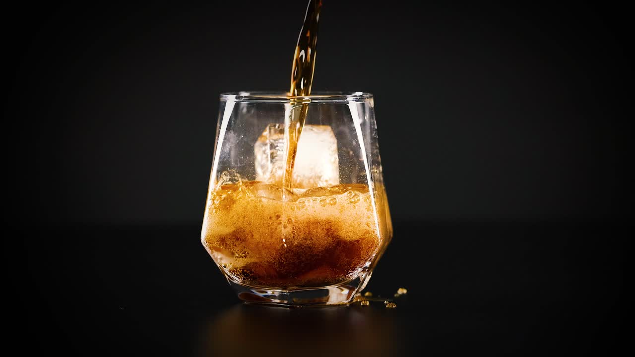 Cola being poured over ice in glass