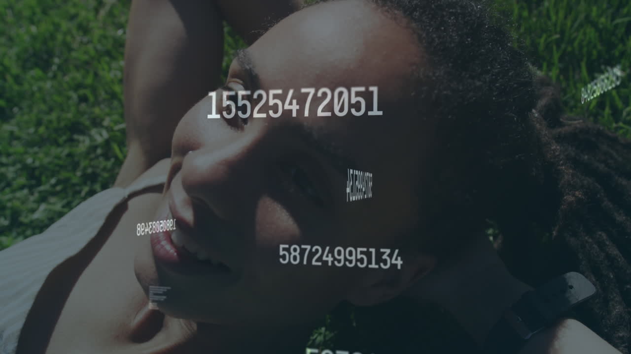 Animation of numbers processing over happy woman lying on grass