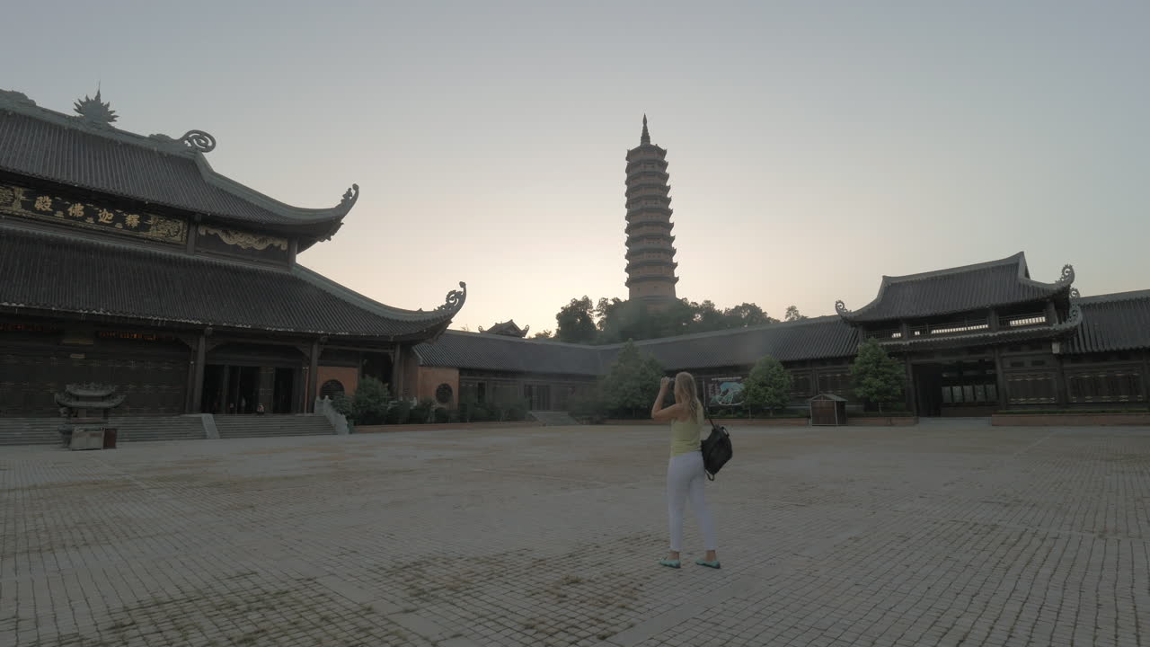 una mujer tomando fotos del templo de bai dinh, vietnam