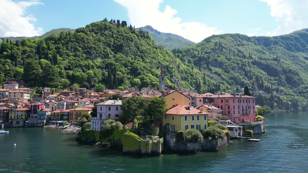Drone view of Varenna on Lake Como, featuring the lakeside church, colorful houses, and mountains reflected in the calm waters