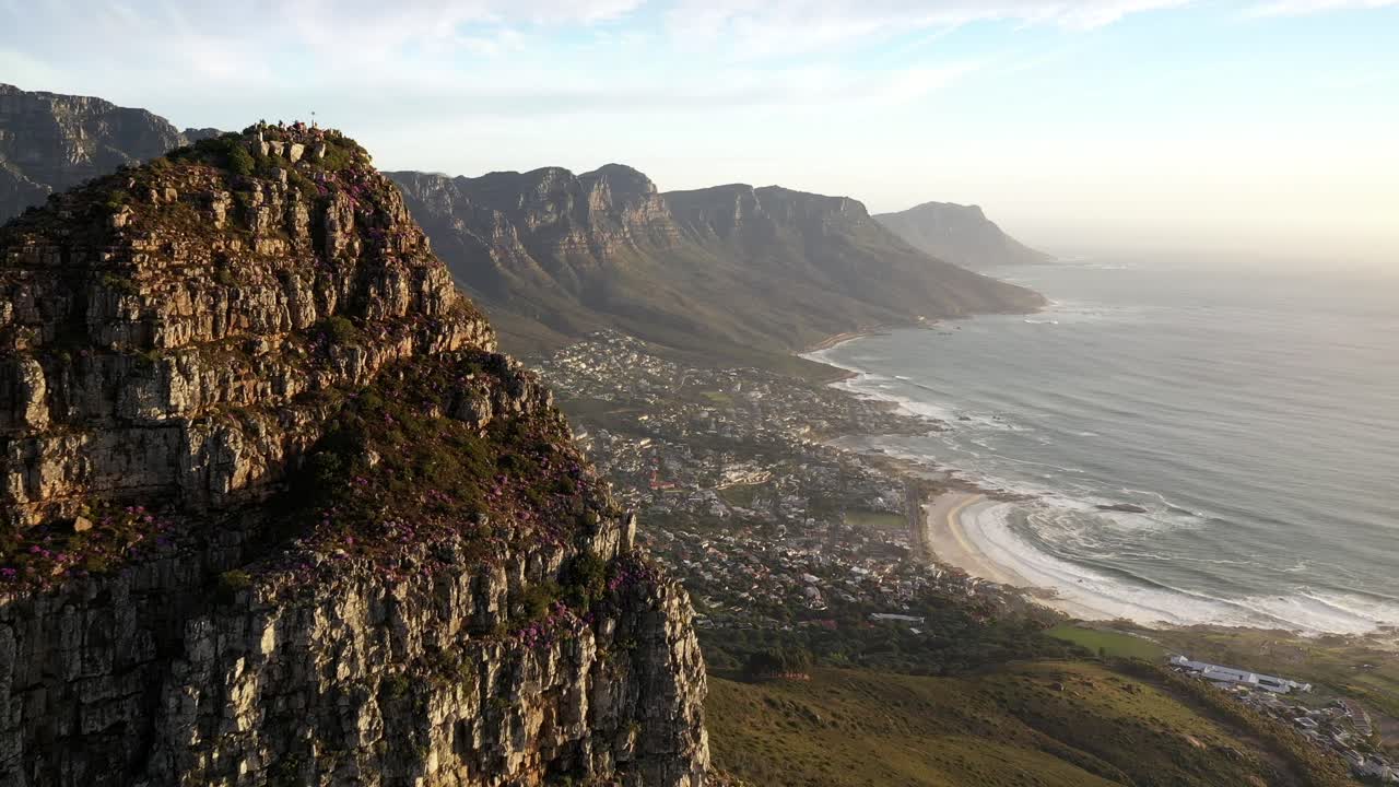 foto aérea cinematográfica do pico da cabeça dos leões da cidade do cabo, revelando a baía de acampamentos e o parque nacional da montanha da mesa durante o pôr do sol da hora de ouro