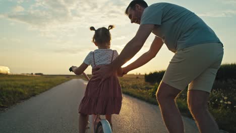 Rückansicht-Eines-Kaukasischen-Vaters,-Der-Seiner-Kleinen-Tochter-Das-Fahrradfahren-Beibringt.