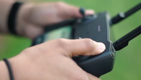 hands turning on drone remote controller outdoors, close up