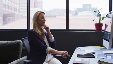 Caucasian-businesswoman-sitting-at-desk-using-a-computer-in-modern-office