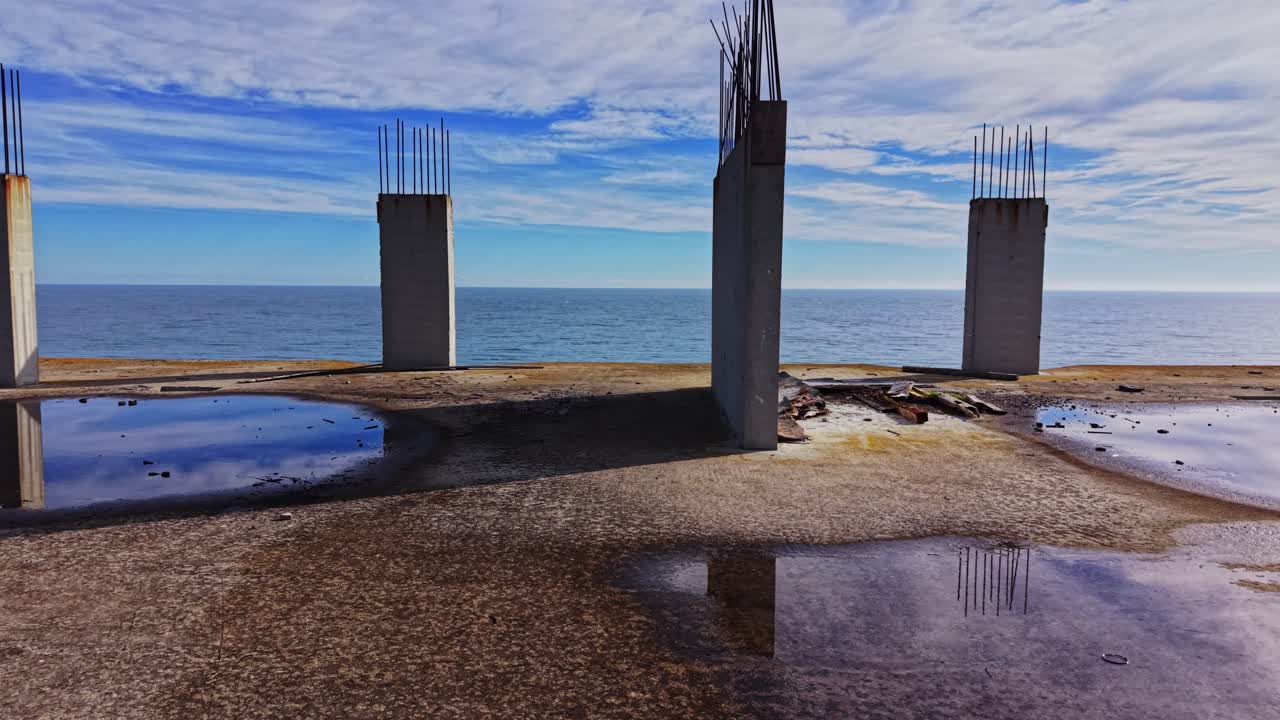 Concrete structure near the ocean with water reflection and serene sky