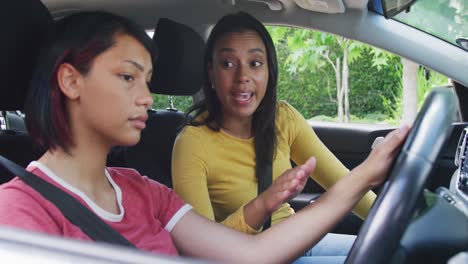 biracial sisters sitting in car and having driving lesson, in slow motion