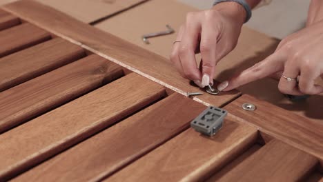 hands assembling wooden furniture with screws and brackets in a well-lit indoor setting