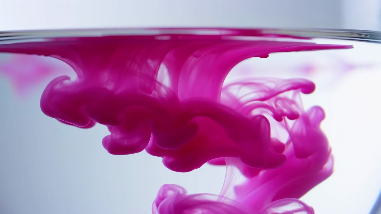 O quadro do meio da sequência mostra tinta rosa magenta dissolvendo e se difundindo em água límpida, criando redemoinhos fluidos, bolhas e fitas