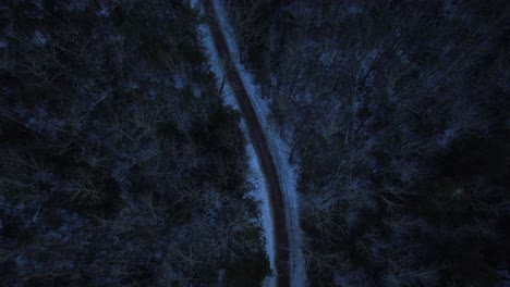 smooth nighttime drone footage of a beautiful road through a snowy winter forest in the appalachian mountains during winter in new york's hudson valley in the catskill mountains sub-range