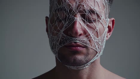 gradual mesh fabric enveloping man's face with closed eyes, symbolizing psychological constriction, emotional entrapment, and silent inner struggle against invisible psychological barriers