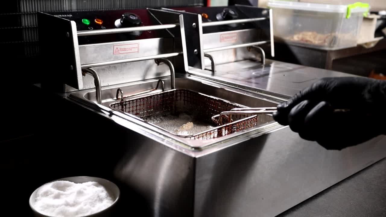chef freyendo comida en una freidora comercial