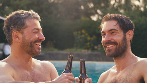 same sex male couple on holiday in swimming pool drinking beer together