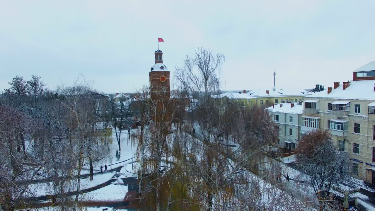 Bare birch-trees in the city park. Drone rising up the square showing the beautiful old tower in the city of Vinnytsia, Ukraine.