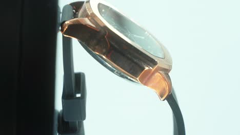 a vertical close up shot of a golden metal hand watch with a black band, modern fashion design, on a 360 rotating stand, studio lighting, slow motion, 4k video