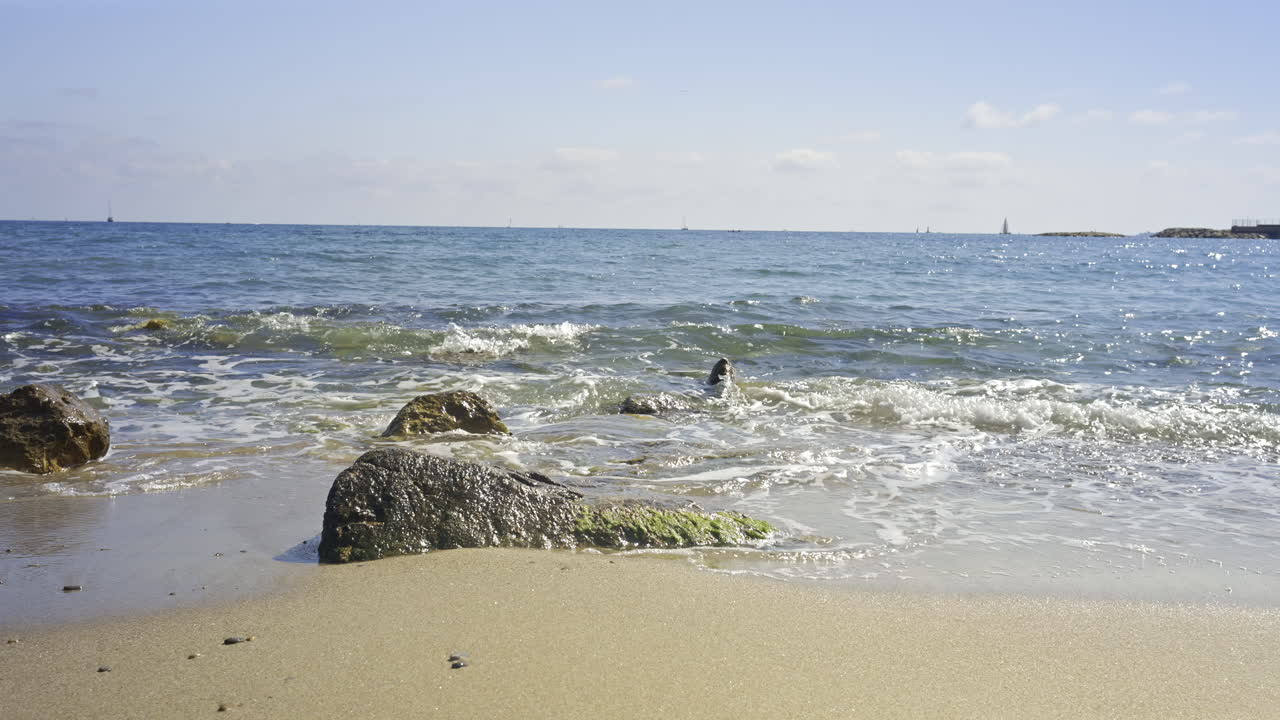 Waves crashing on rocks on a sandy beach in the south of France on a sunny day
