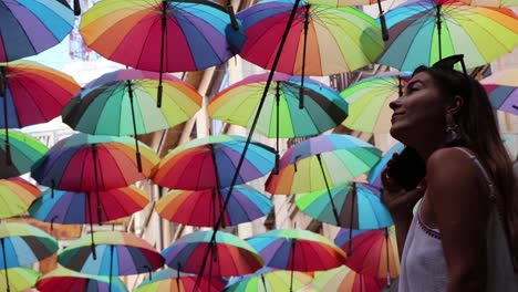 Girl-Talking-On-The-Phone-Looking-At-Colored-Umbrellas-In-Awe