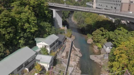 aerial rising and tilt reveal shot revealing beautiful mountainous scenery, bridge and hotel in jozankei famous hot spring onsen town in hokkaido, japan