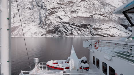 slow motion pov of a winter ferry boat ride in geirangerfjord to geiranger, norway, with snowy mountains and captivating fjord views