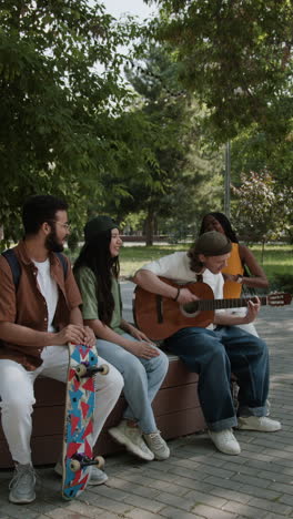 friends playing guitar in the park
