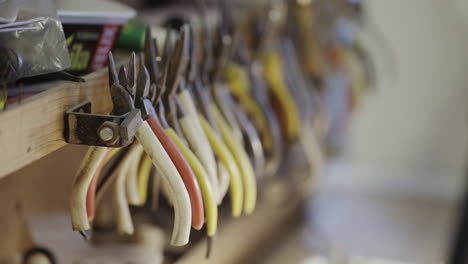 pliers hanging on a tool rack in a jewelry workshop