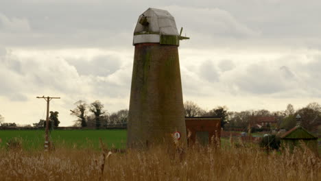 mirando a través de las cañas en un molino de viento abandonado de norfolk broads bomba de agua en el río hormiga cerca del puente ludham