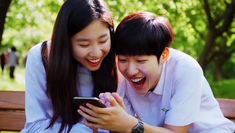 teenagers excitedly looking at a smartphone in a park