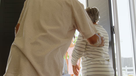 rear view of senior black couple welcoming children at door in a comfortable home 4k